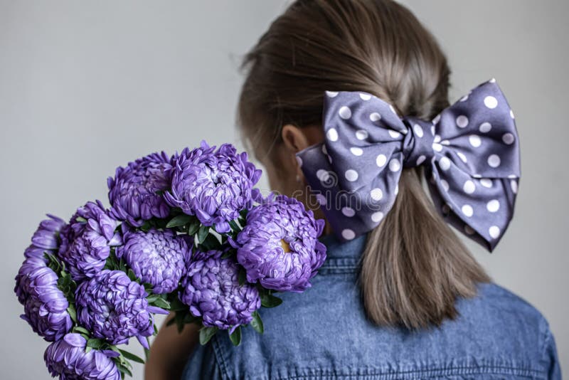 Retrovisore di una bambina che tiene in mano un bouquet di crisantemi blu, spazio fotografia stock