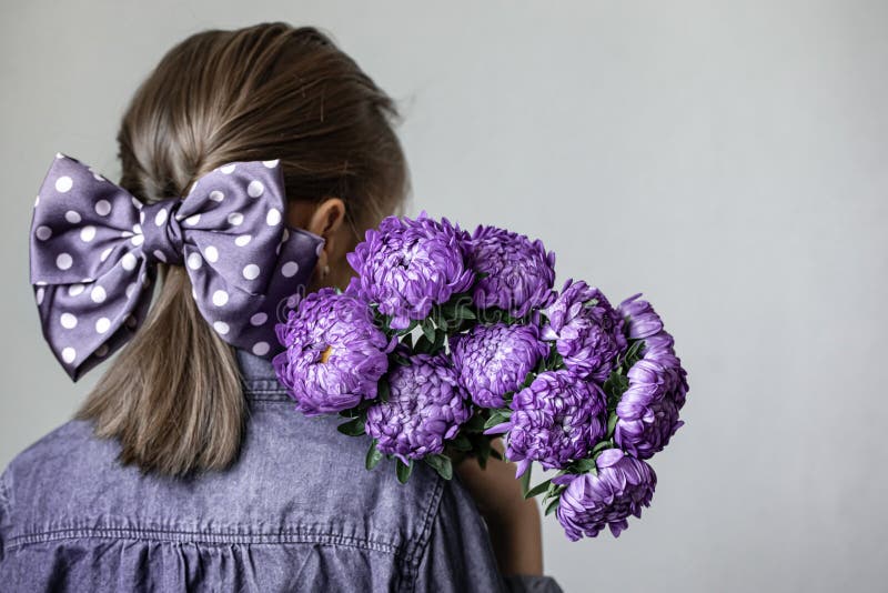 Retrovisore di una bambina che tiene in mano un bouquet di crisantemi blu, spazio fotografia stock