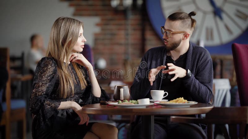 Reunião feliz dos pares na cafetaria Colegas que gastam a pausa para o almoço que considera junto seu negócio Desenhista masculin