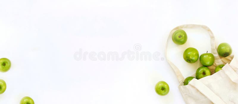 Reusable cotton textile bag with green apples on a white background. The concept of zero waste, green shopping. Banner,Top view