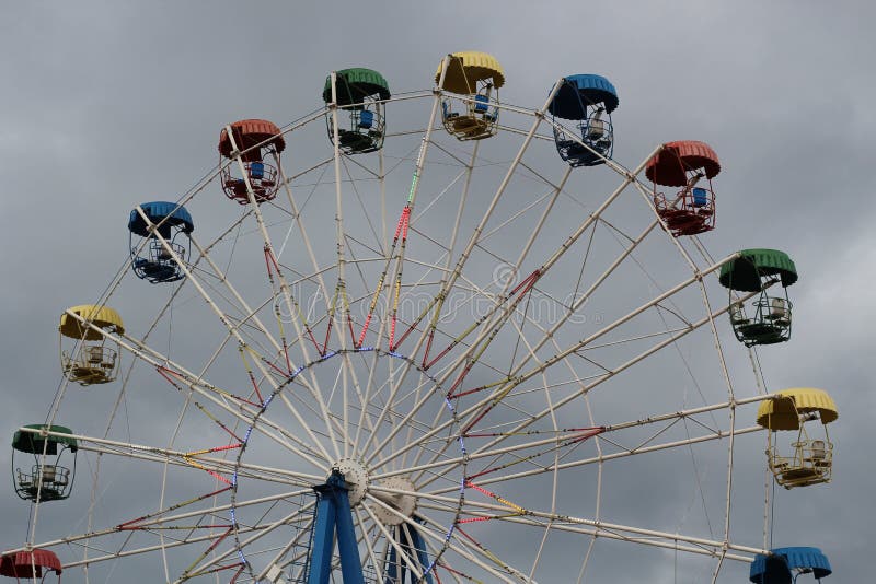 Reuzenrad met kleurrijke cabines in het Pretpark op de achtergrond van de stormachtige hemel royalty-vrije stock fotografie Reuzenrad met kleurrijke cabines in het Pretpark op de achtergrond van de stormachtige hemel royalty-vrije stock fotografie