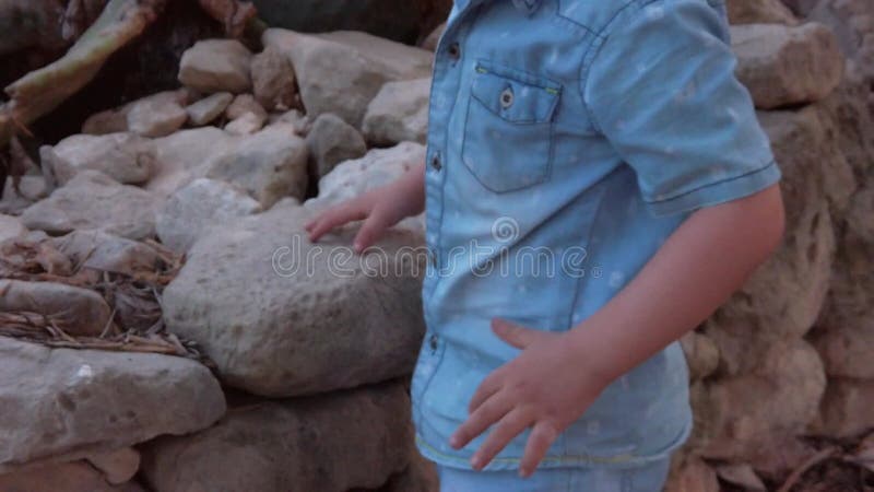 Revelando dedos de pies a hombros niño lindo jugando con una piedra en el parque. movimiento lento