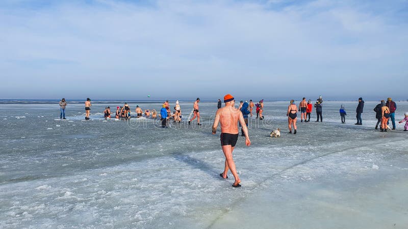 Winter swimming. People winter bathing in the sea. A large group of people is walking on frozen