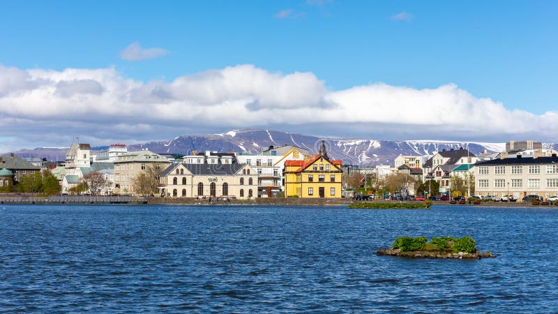 Reykjavik, Iceland, 14.05.22. Reykjavik skyline colorful public and residential buildings by the blue Tjornin lake, snowcapped Mount Esjan in the background. Reykjavik, Iceland, 14.05.22. Reykjavik skyline colorful public and residential buildings by the blue Tjornin lake, snowcapped Mount Esjan in the background