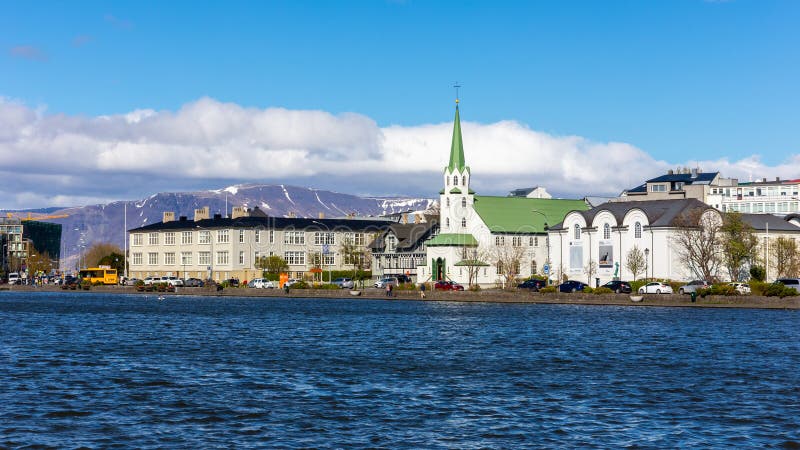 Reykjavik, Iceland, 14.05.22. Reykjavik skyline with Frikirkjan i Reykjavik lutheran church, colorful residential buildings, Tjornin lake and snowcapped Mount Esjan in the background on sunny day. Reykjavik, Iceland, 14.05.22. Reykjavik skyline with Frikirkjan i Reykjavik lutheran church, colorful residential buildings, Tjornin lake and snowcapped Mount Esjan in the background on sunny day