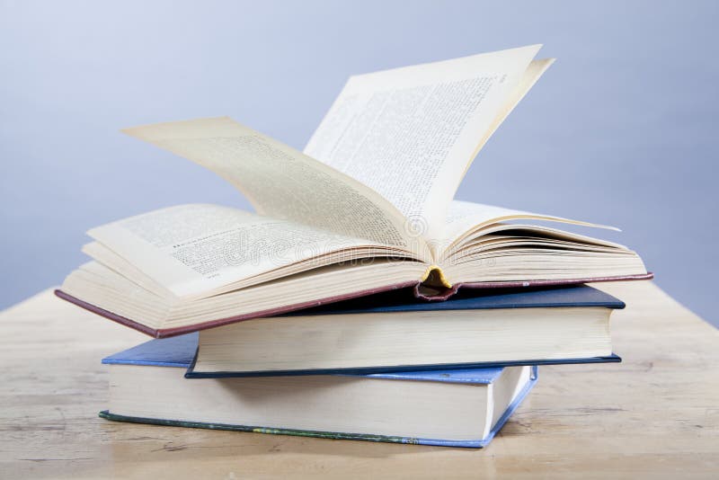 Open book lying on a pile of books on a wooden table. Open book lying on a pile of books on a wooden table