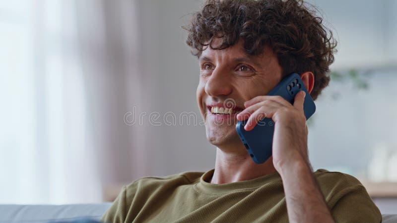 Riant gars parlant téléphone portable sur canapé à la maison le week-end se sentir détendu closeup photographie stock