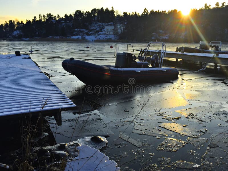 Rib boat in frozen lake with sun going down