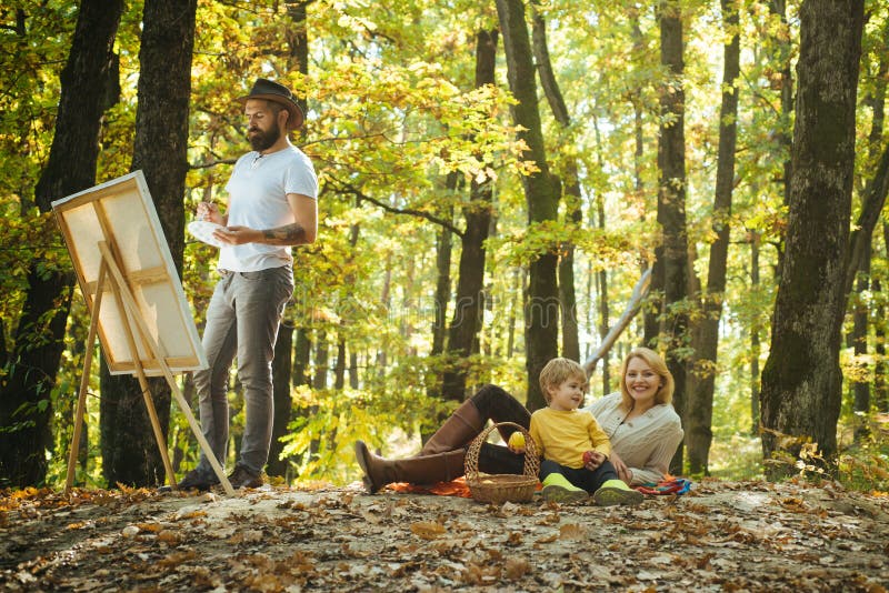 Ricavando dalla vita Artista del pittore con la famiglia che si rilassa nella pittura della foresta in natura Nuova immagine di i fotografia stock Ricavando dalla vita Artista del pittore con la famiglia che si rilassa nella pittura della foresta in natura Nuova immagine di i fotografia stock