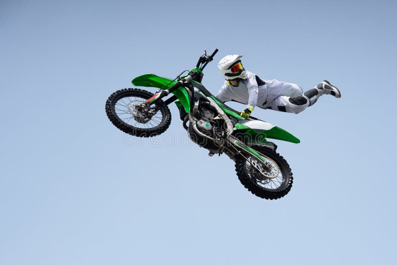 Ricer in a white protective uniform and helmet shares a stunt in the air on a motorcycle.