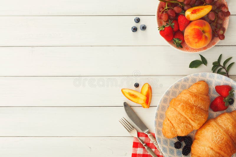 Continental breakfast with croissants and berries on white wood