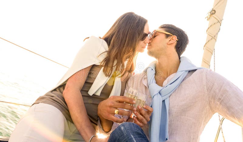 Rich young couple in love on sailboat kissing at sunset - Luxury lifestyle concept sailing around world - Soft focus on warm royalty free stock images Rich young couple in love on sailboat kissing at sunset - Luxury lifestyle concept sailing around world - Soft focus on warm royalty free stock images