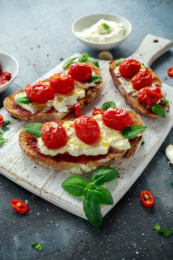 A ricota Bruschetta do tomate com sol secou a pasta de tomates, o pão de mistura do azeite e a manjericão imagens de stock A ricota Bruschetta do tomate com sol secou a pasta de tomates, o pão de mistura do azeite e a manjericão imagens de stock