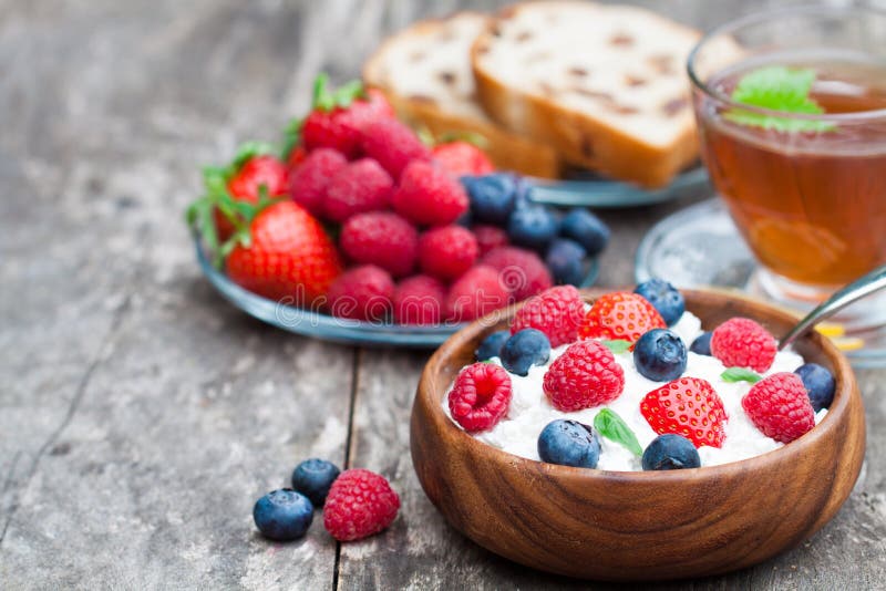 Ricotta sana della prima colazione con le bacche ed il tè della melissa fotografia stock Ricotta sana della prima colazione con le bacche ed il tè della melissa fotografia stock