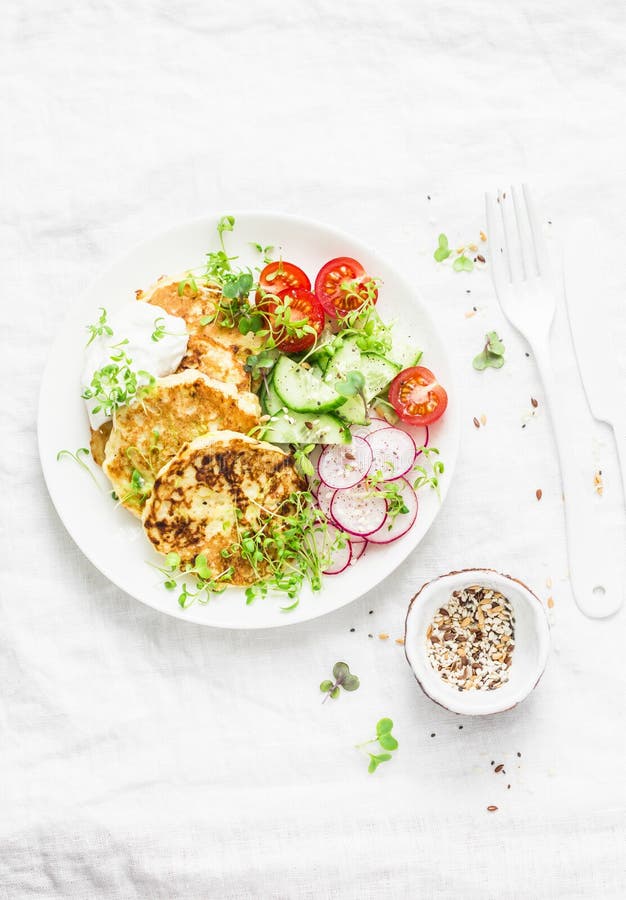 Ricotta zucchini fritters and fresh vegetables salad. Cucumbers, cherry tomatoes, radishes, micro greens and zucchini pancakes on stock images Ricotta zucchini fritters and fresh vegetables salad. Cucumbers, cherry tomatoes, radishes, micro greens and zucchini pancakes on stock images
