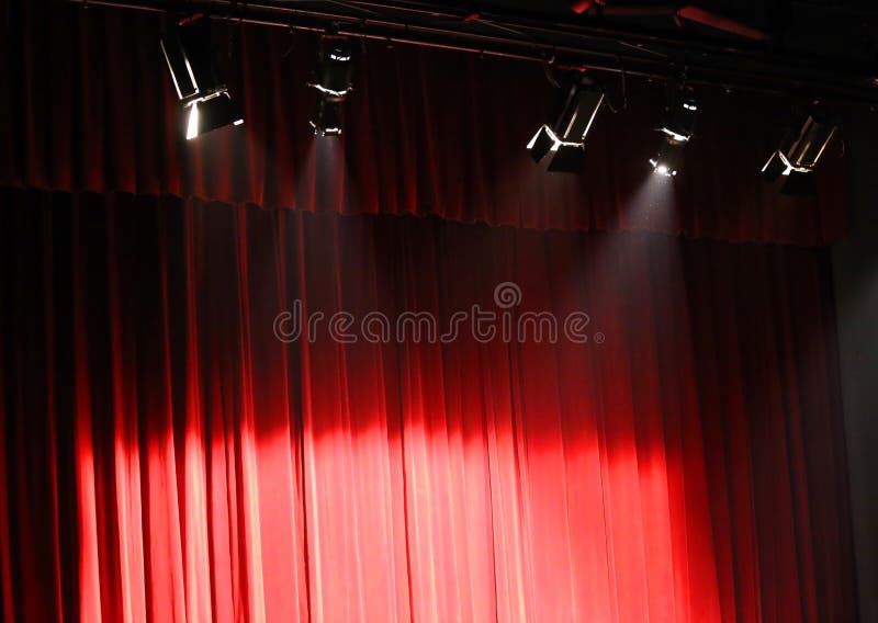 Red theater curtain over the stage and the spotlights projectors. Red theater curtain over the stage and the spotlights projectors