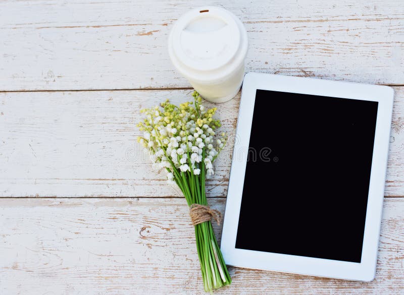 Riduca in pani il computer, un vetro di caffè ed i gigli della valle fotografia stock