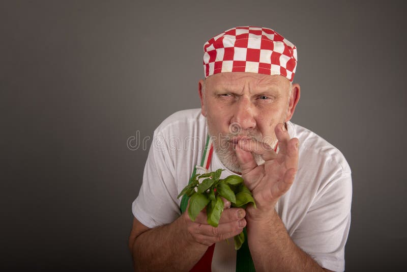 Riechende Basilikumblätter des reifen italienischen Chefs stockfotografie Riechende Basilikumblätter des reifen italienischen Chefs stockfotografie