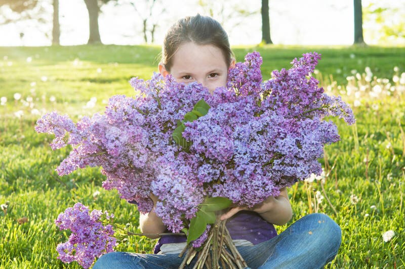 Child smiles and peeks above bouquet while smelling Lilac flowers. Child smiles and peeks above bouquet while smelling Lilac flowers