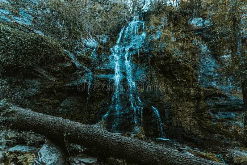 Riesiger Wasserfall in der Mitte des Naturwald mit einem fehlerhaften LKW in der Front im Herbst lizenzfreie stockbilder
