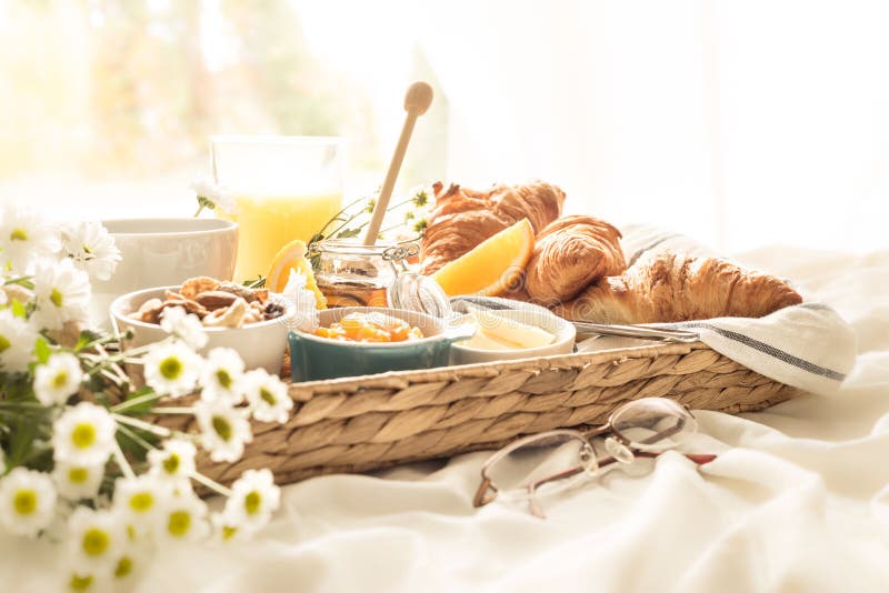 Rieten dienblad met continentaal ontbijt op witte bedbladen royalty-vrije stock afbeeldingen Rieten dienblad met continentaal ontbijt op witte bedbladen royalty-vrije stock afbeeldingen