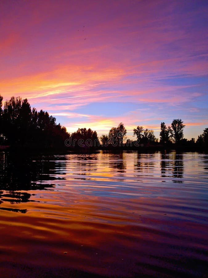 Riflessione pacifica porpora del fiume al tramonto immagine stock libera da diritti Riflessione pacifica porpora del fiume al tramonto immagine stock libera da diritti