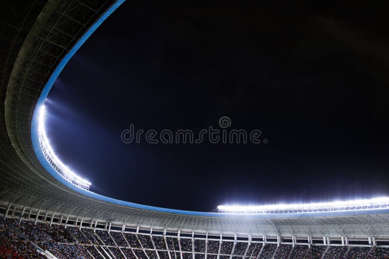 Riflettori e proiettori ad uno stadio alla notte immagine stock Riflettori e proiettori ad uno stadio alla notte immagine stock