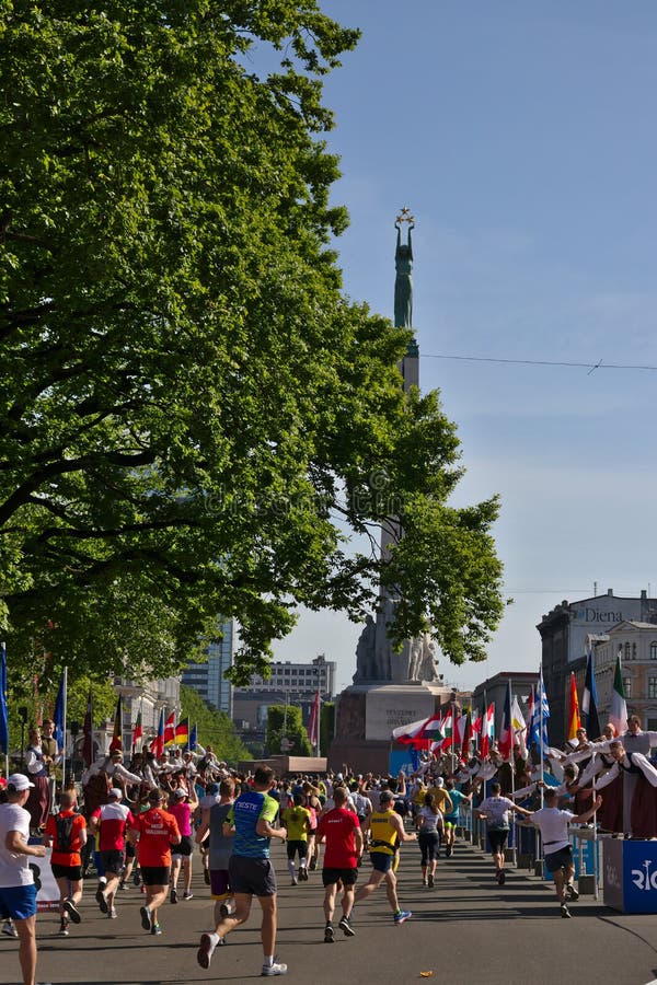 Riga, Lettland - 19. Mai 2019: Die Marathonl?ufer, die Freiheitsstatue mit traditionsgem?? gekleideten Cheerleadern erreichen, ge stockfotos Riga, Lettland - 19. Mai 2019: Die Marathonl?ufer, die Freiheitsstatue mit traditionsgem?? gekleideten Cheerleadern erreichen, ge stockfotos
