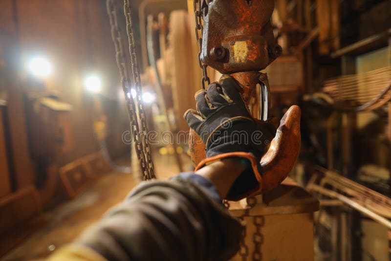 Rigger high risk worker wearing a safety glove while inspecting crane lifting lug clipped