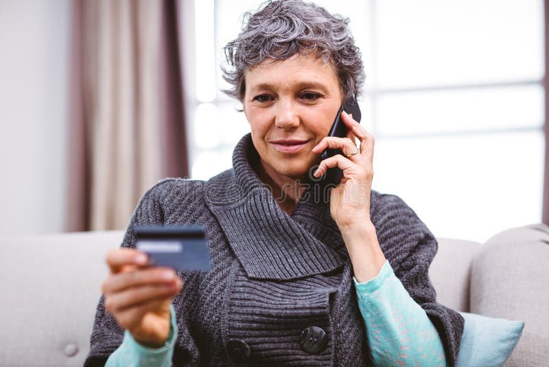Rijp de creditcard van de vrouwenholding terwijl het spreken op mobiele telefoon royalty-vrije stock fotografie Rijp de creditcard van de vrouwenholding terwijl het spreken op mobiele telefoon royalty-vrije stock fotografie
