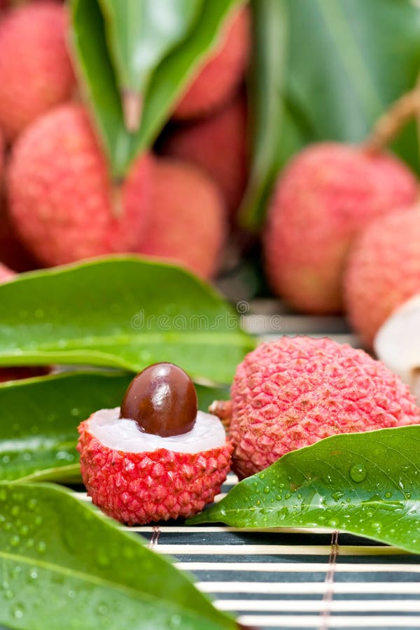 Halved lychee fruit showing seed with green leaves decoration. Halved lychee fruit showing seed with green leaves decoration.