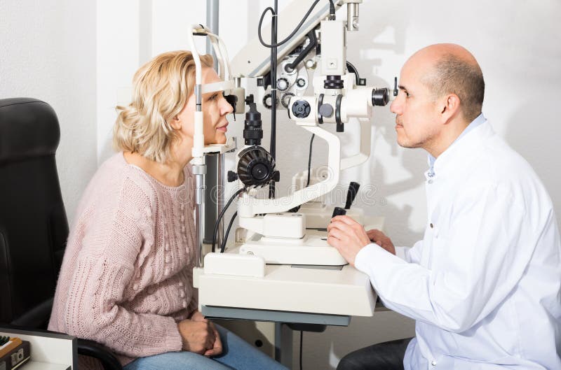 Rijp opticien examinating zicht met hulp van spleetlamp stock foto Rijp opticien examinating zicht met hulp van spleetlamp stock foto