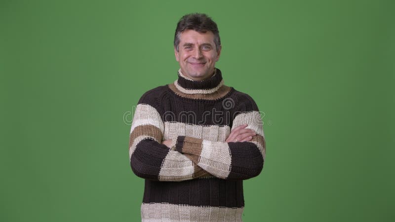 Rijpe knappe mens die colsweater dragen tegen groene achtergrond