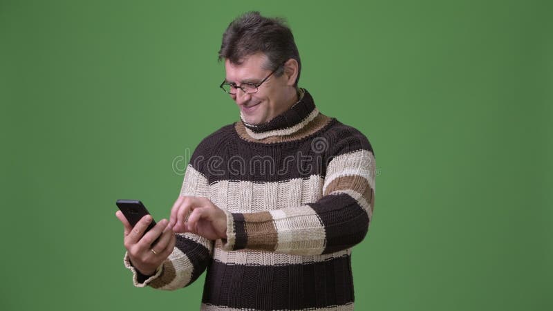 Rijpe knappe mens die colsweater dragen tegen groene achtergrond