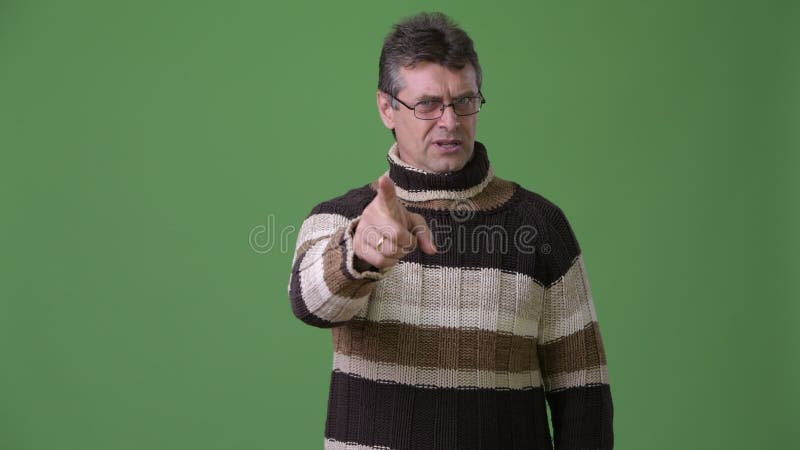 Rijpe knappe mens die colsweater dragen tegen groene achtergrond