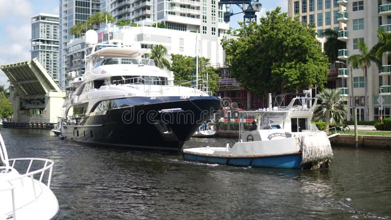 Rimorchiatore che traina un grosso yacht in un canale del centro città durante il giorno a florida