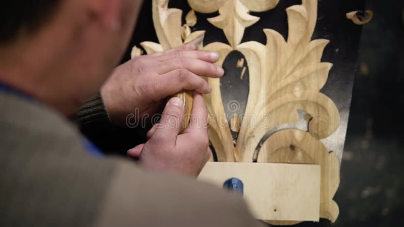 Rinchiuso le immagini delle mani dell'uomo, sta curando un piccolo dettaglio sulla sagoma di legno - ornamento floreale in opera