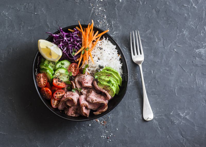 Beef steak, rice and vegetable power bowl. Healthy balanced food concept. On a dark background, top view. Beef steak, rice and vegetable power bowl. Healthy balanced food concept. On a dark background, top view