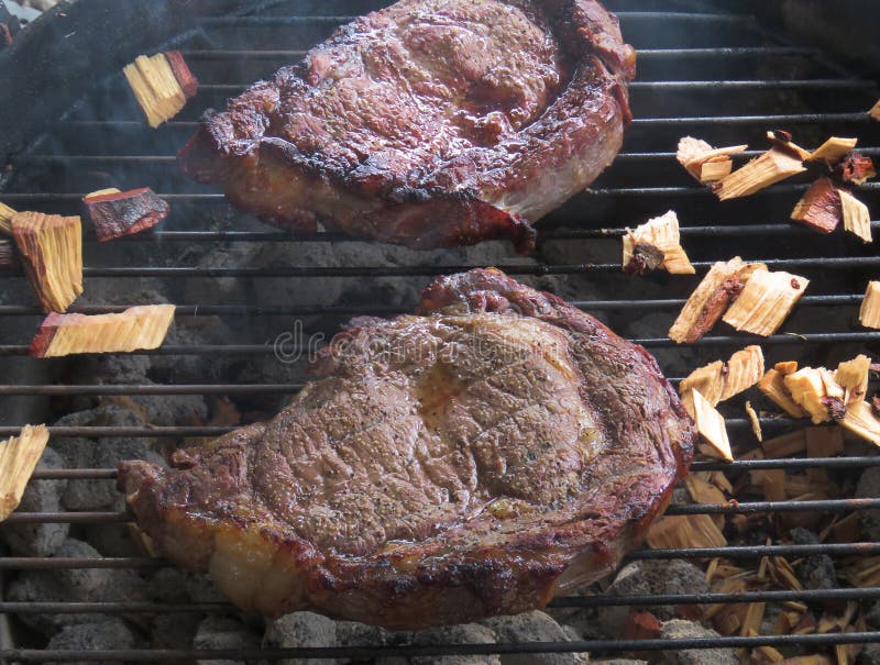 Rindfleischsteaks mit Holzspänen auf einer Holzkohle grillen lizenzfreie stockfotografie Rindfleischsteaks mit Holzspänen auf einer Holzkohle grillen lizenzfreie stockfotografie