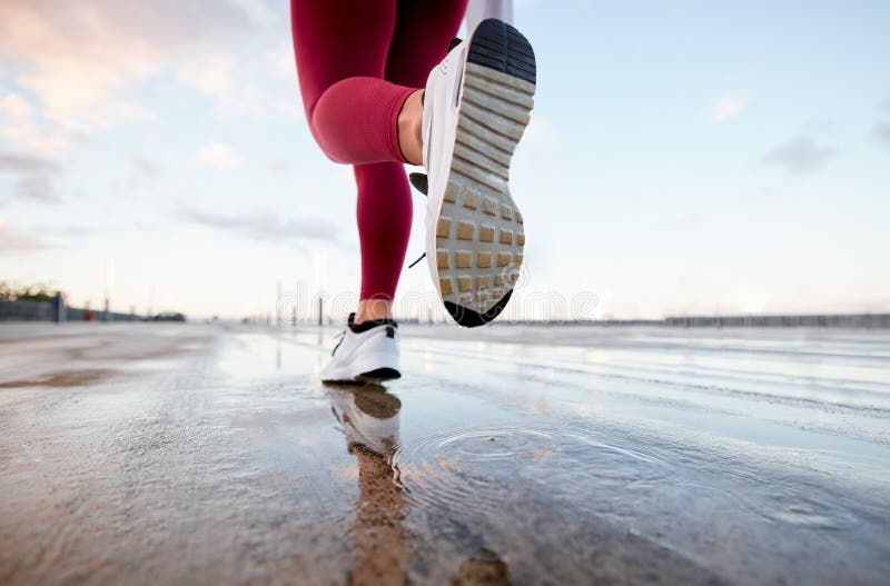 Rinnande regn och fötter av kvinna med träning och morgonmaratonutbildning på gatan. Vattenskrymd arkivbild