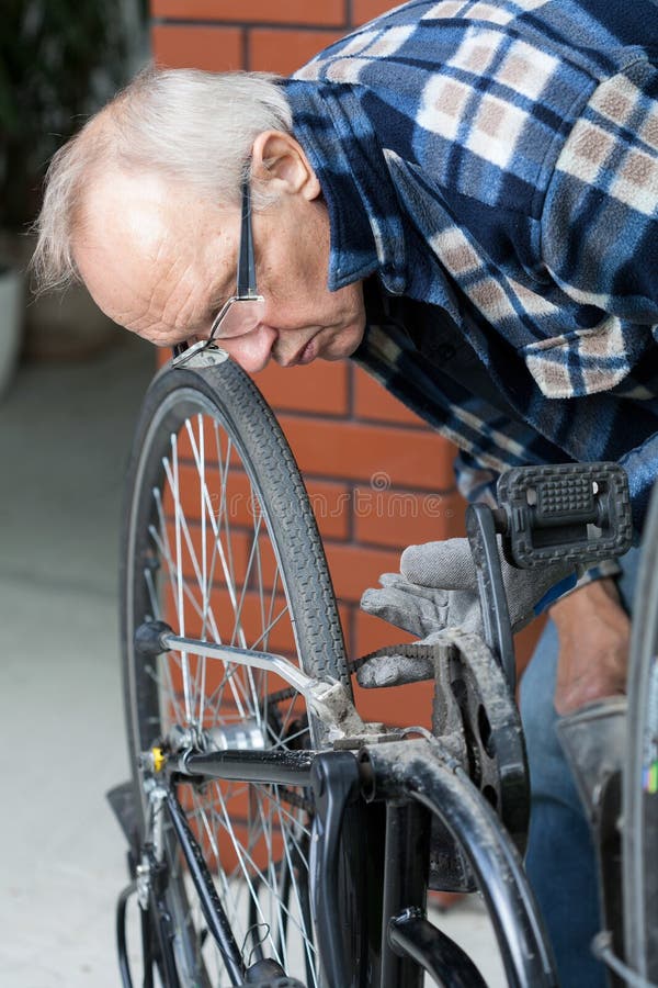 Riparatore che controlla la catena della bicicletta immagini stock libere da diritti Riparatore che controlla la catena della bicicletta immagini stock libere da diritti