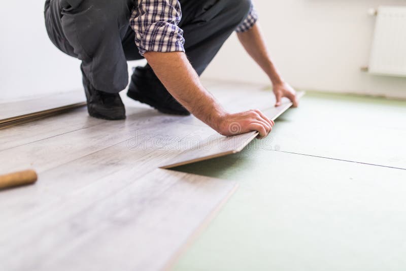 Riparazione, costruzione e concetto domestico - vicini su delle mani maschii che intalling pavimentazione di legno fotografia stock Riparazione, costruzione e concetto domestico - vicini su delle mani maschii che intalling pavimentazione di legno fotografia stock