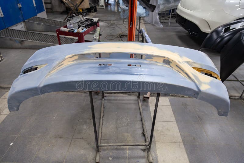 Riparazione del paraurti posteriore di un'automobile blu dopo un incidente con l'aiuto di di mastice colorato multi in un'officin fotografia stock libera da diritti Riparazione del paraurti posteriore di un'automobile blu dopo un incidente con l'aiuto di di mastice colorato multi in un'officin fotografia stock libera da diritti