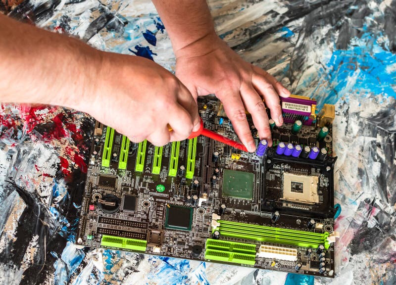 Riparazione di una scheda madre del PC con un cacciavite con una maniglia rossa immagine stock libera da diritti Riparazione di una scheda madre del PC con un cacciavite con una maniglia rossa immagine stock libera da diritti