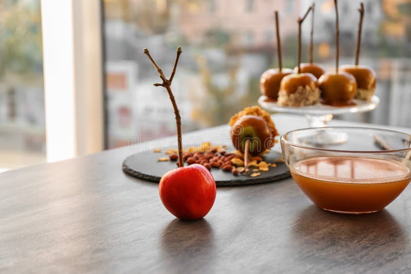 Ripe apple and glass bowl with caramel on grey table