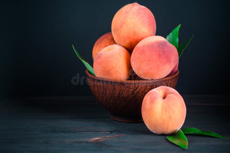 Ripe aromatic peach with leaves on a wooden table