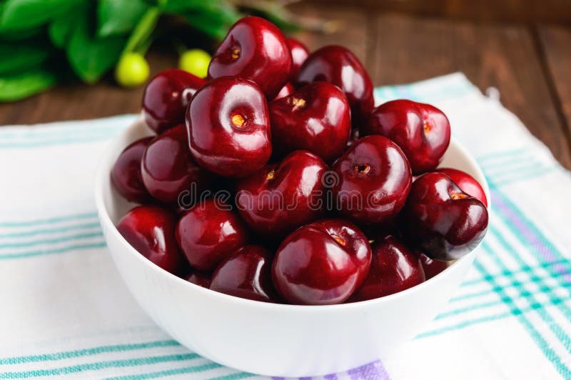 Ripe black cherries in a white bowl on a light background. royalty free stock photo