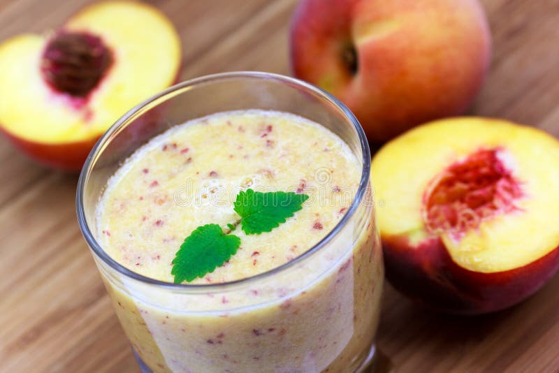 Ripe half of peach, smoothie of peach, on wooden b