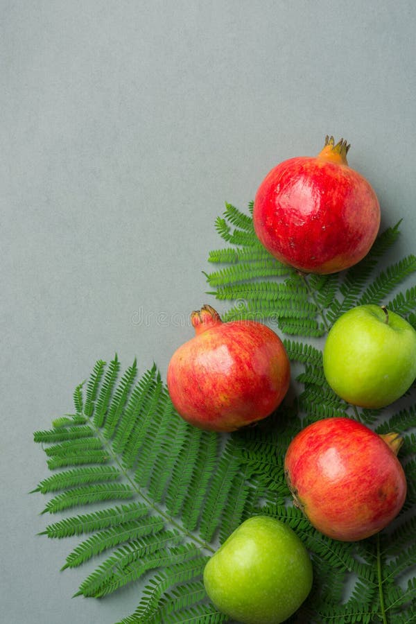 Ripe juicy organic bright red pomegranates green apples fern branches on grey stone background. Fall produce harvest royalty free stock photos Ripe juicy organic bright red pomegranates green apples fern branches on grey stone background. Fall produce harvest royalty free stock photos