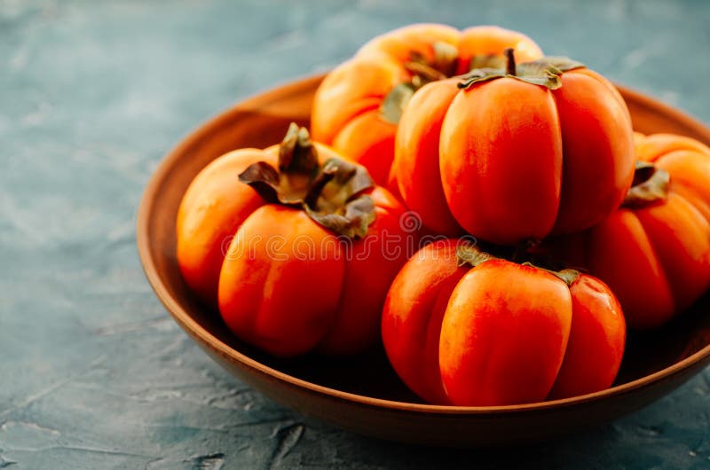 Ripe Orange Persimmon Fruit in a Ceramic Plate. Persimmon is a Source of Calcium, a Source of